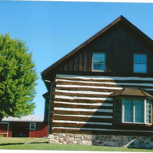 Rustic log cabin with stone foundation finished in Tobacco