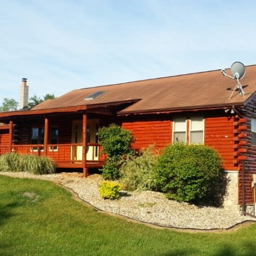 Red log cabin with front porch finished in Timbertone