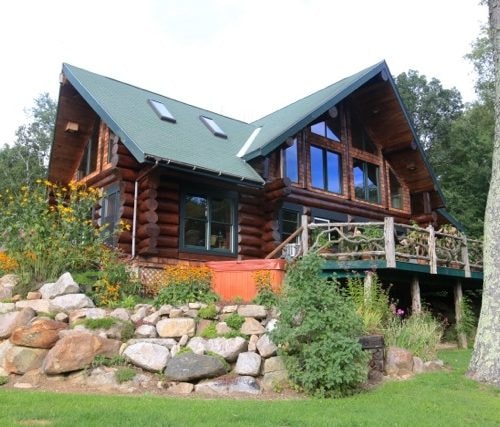Log cabin with green roof finished in Redwood Dark