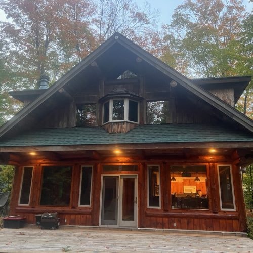 Rustic cabin with lit windows finished in Men-Wood Coatings